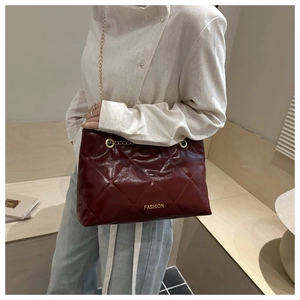 Dettaglio borsa trapuntata rosso vino con catena dorata e scritta Fashion