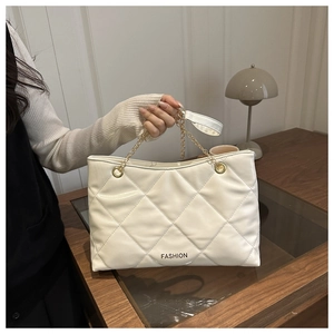 Dettaglio della borsa shopper bianca trapuntata con catena dorata e stampa fashion