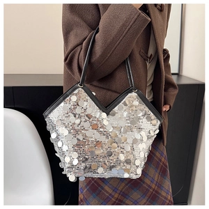 Detail of silver sequin tote bag with large round scales and contrasting black leather straps