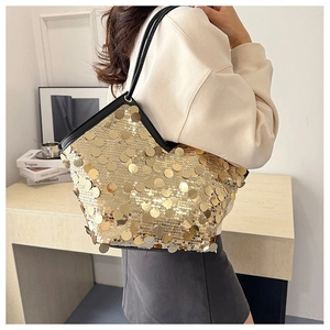 Detailed close-up of large gold sequins on tote bag with black leather handle