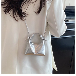 Detail showing metallic silver mini handbag with circular handle and brand logo print