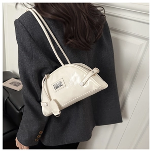 Detail of cream-white glossy patent leather shoulder bag with metallic logo and sleek straps