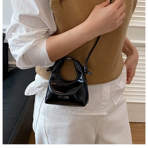 Detail of black patent leather mini crossbody bag featuring white HYLLZZA letter logo