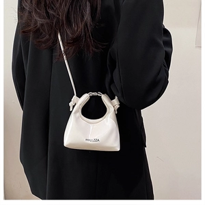 Close-up of a white patent leather mini bag featuring round handle and metal hardware