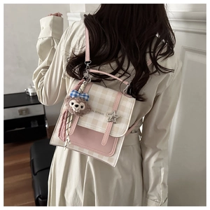 Detail view of pink and white checkered dual-use backpack with star buckle and plush charm