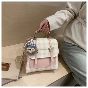 Detail of pink plaid handbag featuring star buckles and a cute plush bear charm