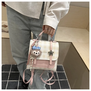 Detail of cream plaid backpack with pink faux leather and cute plush bear charm