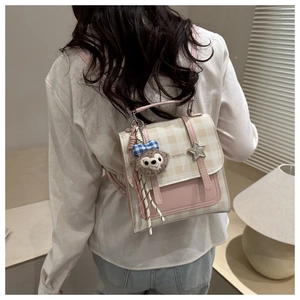 Detail of checkered plaid backpack with pink trim and a cute plush doll keychain charm