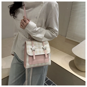Detail of pink plaid crossbody bag featuring silver star buckles and brand text
