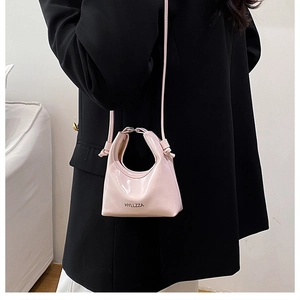 Close-up of a pink patent leather crossbody mini bag with polished finish and top handle