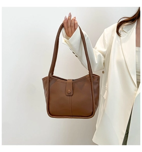 Dettaglio della borsa tote in pelle marrone con fibbia rotonda e cuciture decorative fini