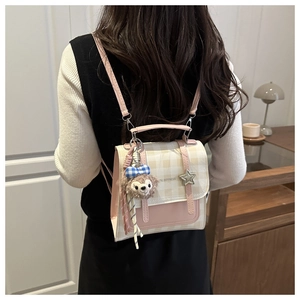 Detail view of pink plaid mini backpack with star pendant and plush toy charm on model