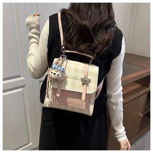 Detail of pink and plaid backpack with star buckle and plush charm on model