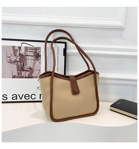 Dettaglio della borsa tote beige con finiture in pelle marrone e chiusura in metallo