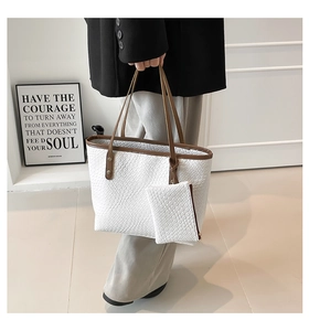 Dettaglio della borsa tote intrecciata con finiture in pelle marrone e mini pochette