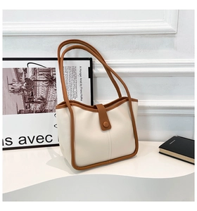 Dettaglio borsa tote retrò color crema con finiture marroni e fibbia magnetica su piedistallo