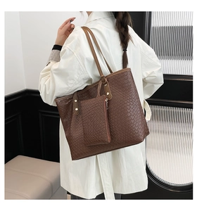 Dettaglio di un set borsa tote intrecciata marrone con pochette abbinata su cappotto bianco