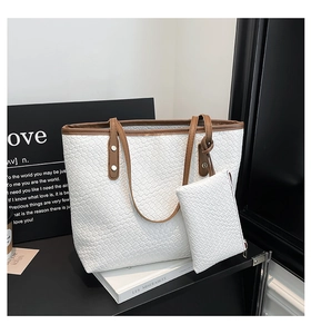 Dettaglio della borsa tote intrecciata bianca con manici in pelle marrone e mini astuccio