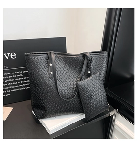 Dettaglio della borsa tote nera intrecciata con rivetti argentati su sfondo minimalista