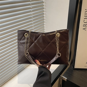 Borsa tote trapuntata marrone scuro con catena dorata e finitura lucida su modella
