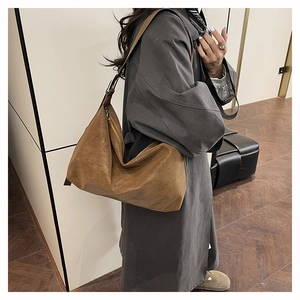 Dettaglio della grande borsa hobo vintage in pelle marrone cerata indossata con un cappotto