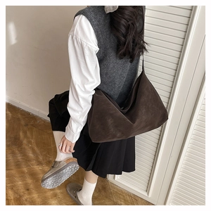 Borsa tote in pelle opaca testa di moro indossata a tracolla su un modello alla moda