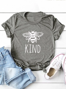 T-shirt grigio scuro KIND con ape, pantaloncini di jeans e sneakers su legno