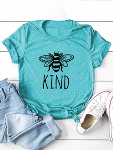 Dettaglio maglietta blu 'Bee Kind' con orlo annodato su pavimento bianco con jeans