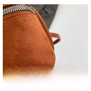 Dettaglio della texture in pelle scamosciata arancio-marrone e cerniera in metallo argento