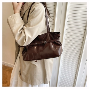 Dettaglio della borsa tote in pelle marrone scuro con cintura con occhielli argentati lucidi