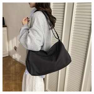 Vue détaillée d'un grand sac de voyage noir en nylon avec une bandoulière réglable sur modèle