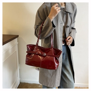 Vista dettagliata della borsa tote in vernice bordeaux con fibbia argento e tracolla regolabile