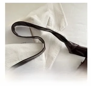 Détail du sac à main en cuir PU marron foncé brillant avec un nœud décoratif sur la sangle