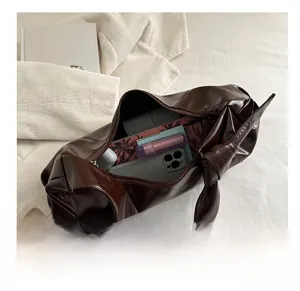 Vue de dessus de l'intérieur spacieux d'un sac bandoulière marron foncé avec essentiels