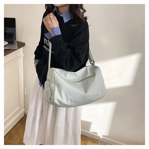 Détail d'un sac de voyage en nylon vert clair porté par un mannequin en mode décontracté