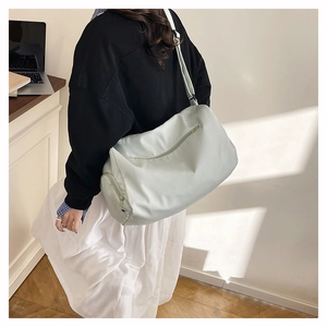 Detail view of light green nylon cylinder bag showing zipper pockets and adjustable strap