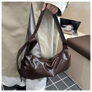 Detail of dark brown glossy hobo bag featuring a decorative side knot and silver zipper