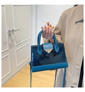 Dettaglio della borsa blu in pelle coccodrillo con chiusura a scatto triangolare in metallo