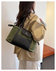 Detail of army green canvas tote bag with black leather pockets and wide shoulder strap