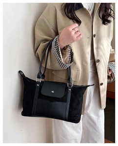 Close-up of black crossbody travel bag with matte leather texture and silver studs