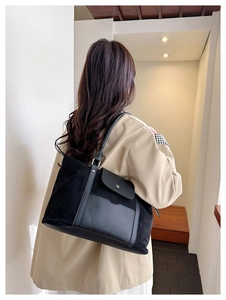 Detail of black large capacity travel tote bag with flap pocket on shoulder model