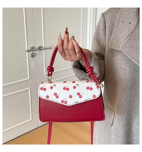 Detail of red and white cherry print small square bag with unique twisted round handle