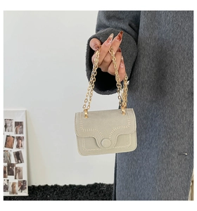Vista dettagliata della borsa beige con cuciture ondulate e eleganti catene dorate