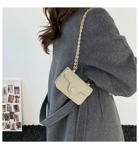 Modella che indossa una borsa a tracolla verde menta con cuciture e catena dorata