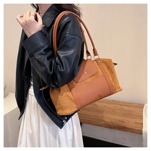 Detail of vintage brown large travel tote bag showing suede and leather texture on a shoulder