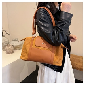 Detail of vintage-style large travel tote featuring brown suede and buckle outer pocket