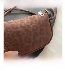 Close-up of leopard print crossbody bag featuring matte texture and brand logo lettering