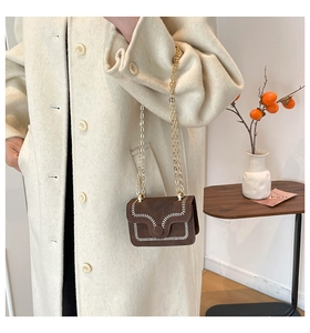 Dettaglio mini borsa in camoscio marrone scuro con cucitura a V e catena dorata