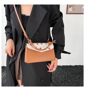 Close-up of heart bear print crossbody bag styled with a stylish black trench coat