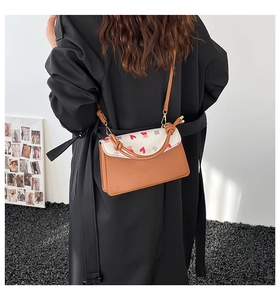 Detail of a brown and white crossbody bag with heart pattern and rope knot decor